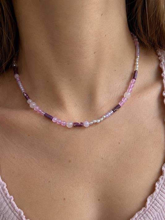 Collar Malva artesanal sobre modelo, elaborado con cuentas de cristal en tonos malva y rosa, detalles nacarados y cierre de acero inoxidable.