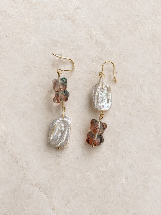 Pendientes Barroca Dulce hechos a mano con perlas barrocas y ositos de cristal en tonos suaves, sobre fondo de piedra beige.