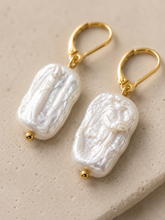 Pendientes Barroca hechos a mano con perlas barrocas rectangulares y cierres dorados, fotografiados sobre fondo de piedra beige.