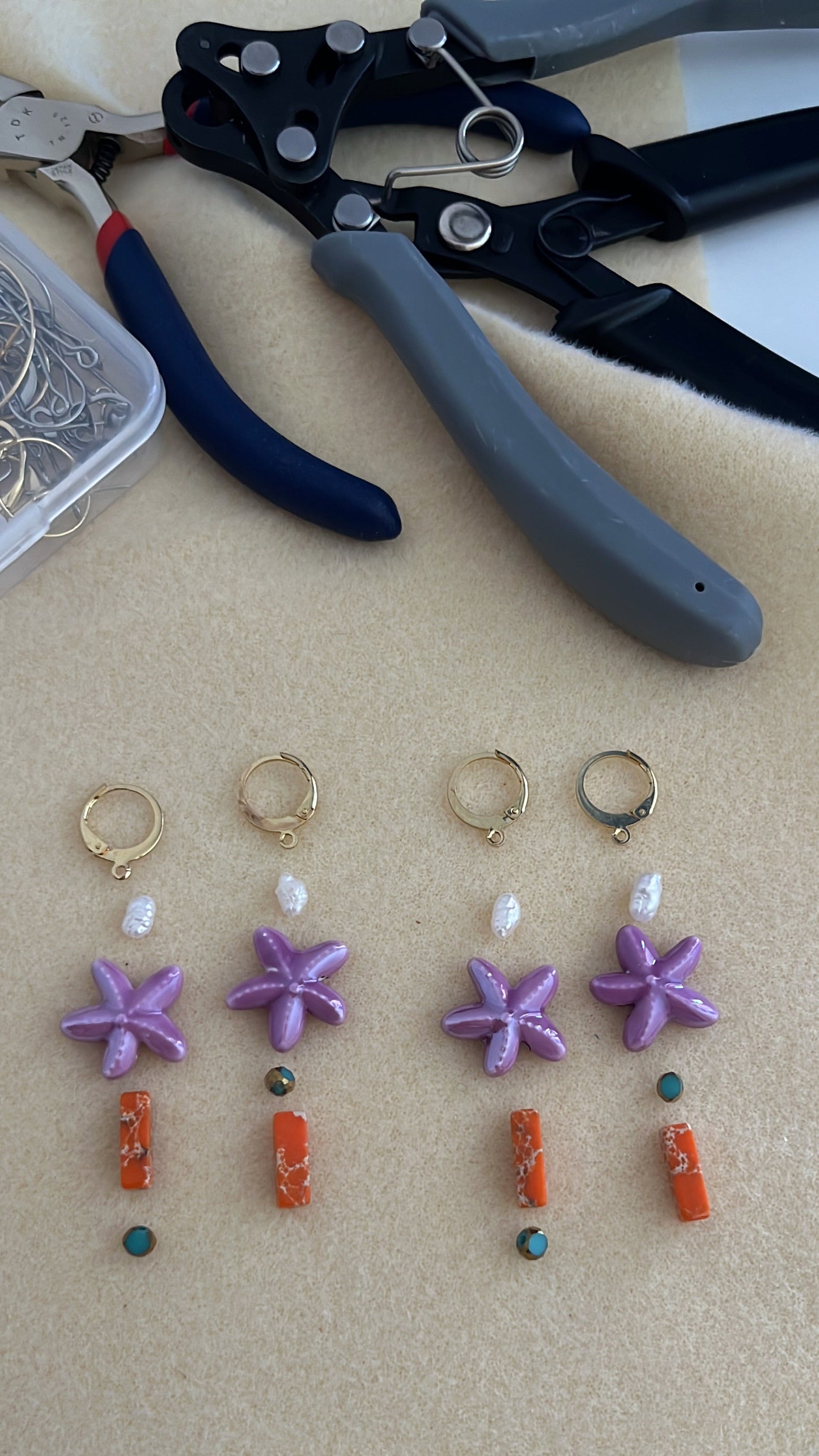 Componentes de los pendientes Mediterráneo dispuestos para su elaboración artesanal, con estrellas de mar moradas, perlas, cuentas coral y detalles turquesa.