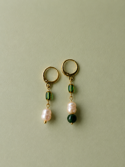 Pendientes artesanales Prao con perlas barrocas de agua dulce, cuentas de vidrio verde y piedra verde oscura, montados en aros de acero inoxidable dorado y con diseño asimétrico.