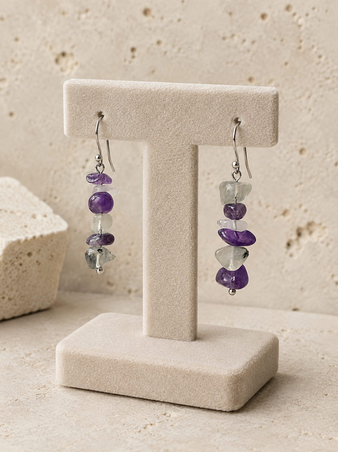 Pendientes Verena expuestos en soporte de joyería, elaborados con amatista y fluorita natural en tonos violeta, blanco y verde, con gancho de acero inoxidable.