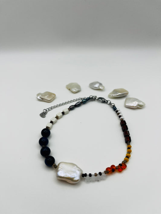Pulsera artesanal Solana con perla barroca blanca, ónix azul marino, ámbar natural, cristal granate y amarillo, rodeada de perlas barrocas sueltas, montada a mano en Murcia
