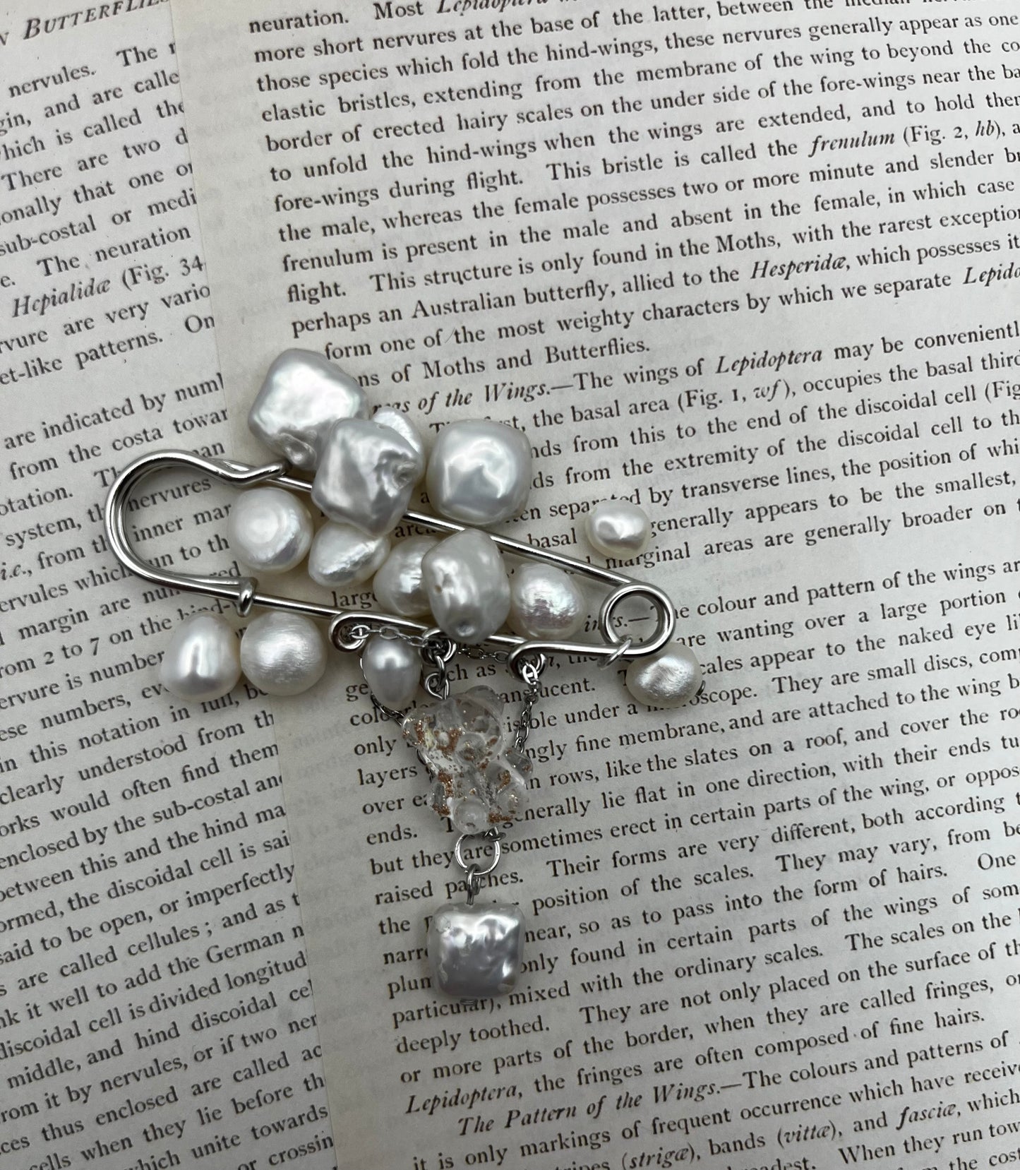 Broche Barroca Dulce – imperdible plateado con racimo de perlas barrocas blancas de agua dulce y cadena con cuentas de cristal facetado transparente y perla barroca colgante, hecho a mano en Murcia
