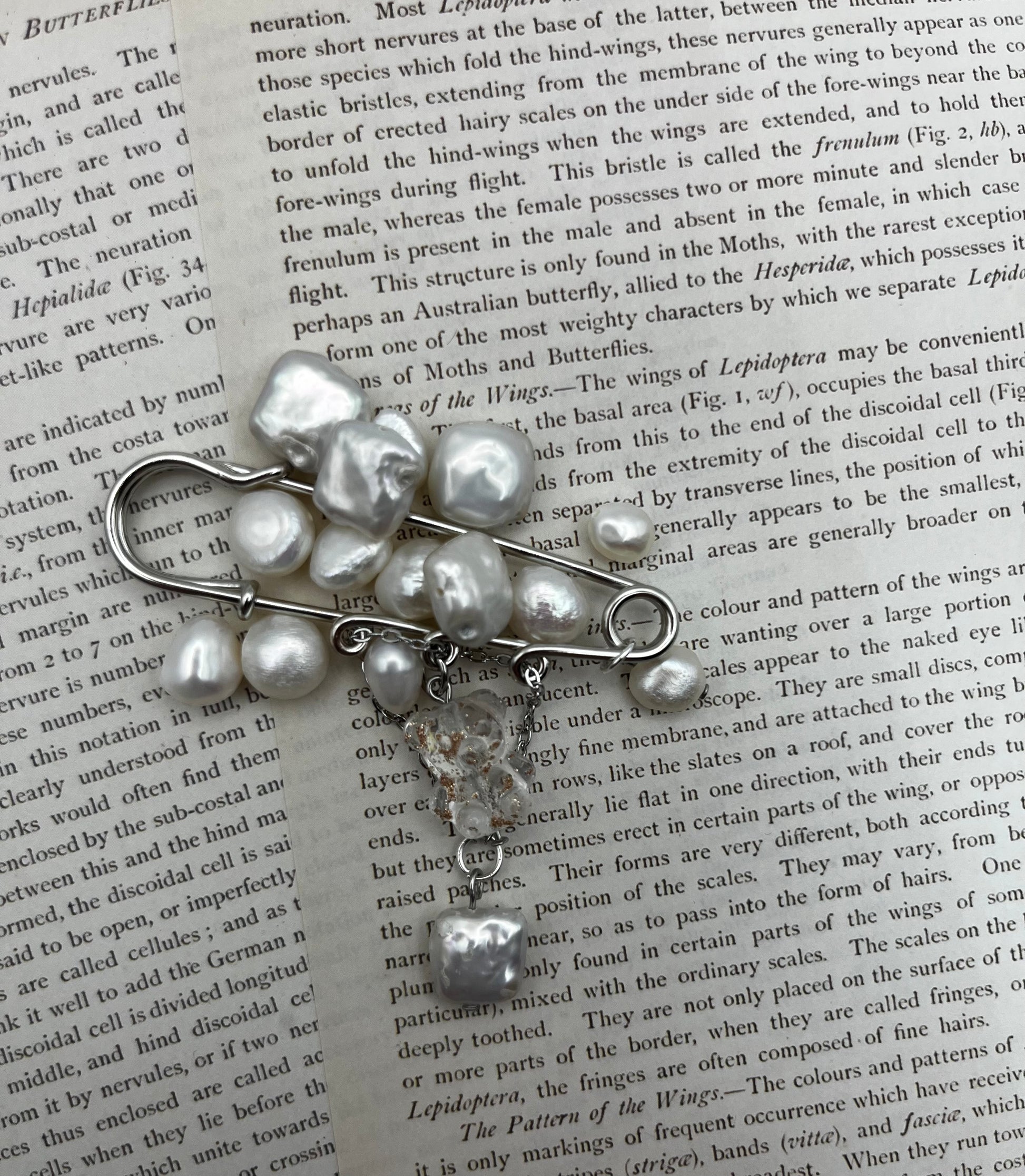 Broche Barroca Dulce – imperdible plateado con racimo de perlas barrocas blancas de agua dulce y cadena con cuentas de cristal facetado transparente y perla barroca colgante, hecho a mano en Murcia