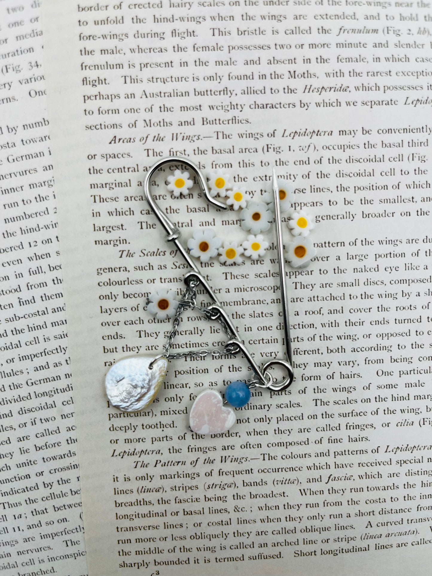 Broche Periwinkle – imperdible plateado con pieza gota de nácar, cuenta azul, corazón rosa y flores de margarita, hecho a mano en Murcia
