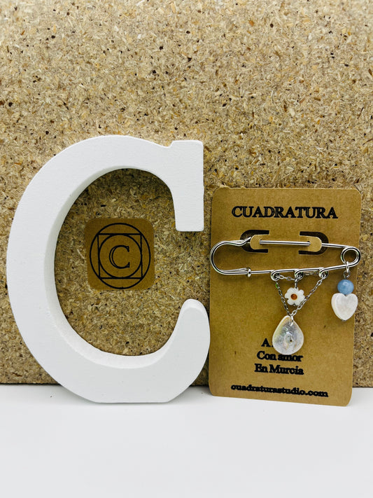 Broche Periwinkle – imperdible plateado con flor de margarita, cuenta azul, corazón de nácar y pieza gota de nácar, presentado en tarjeta Cuadratura, hecho a mano en Murcia
