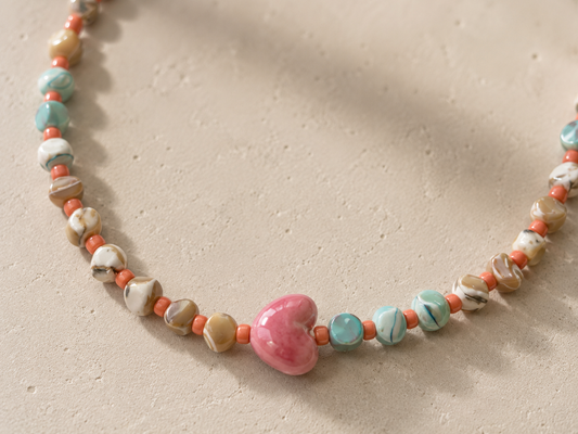 Detalle del collar Calma hecho a mano con corazón de cerámica y piedras naturales.