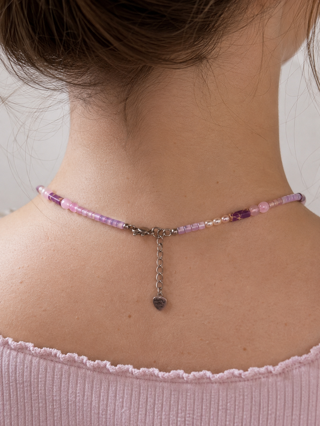 Parte trasera del collar Malva mostrando el cierre de acero inoxidable, la cadena extensora y el colgante decorativo en forma de corazón.