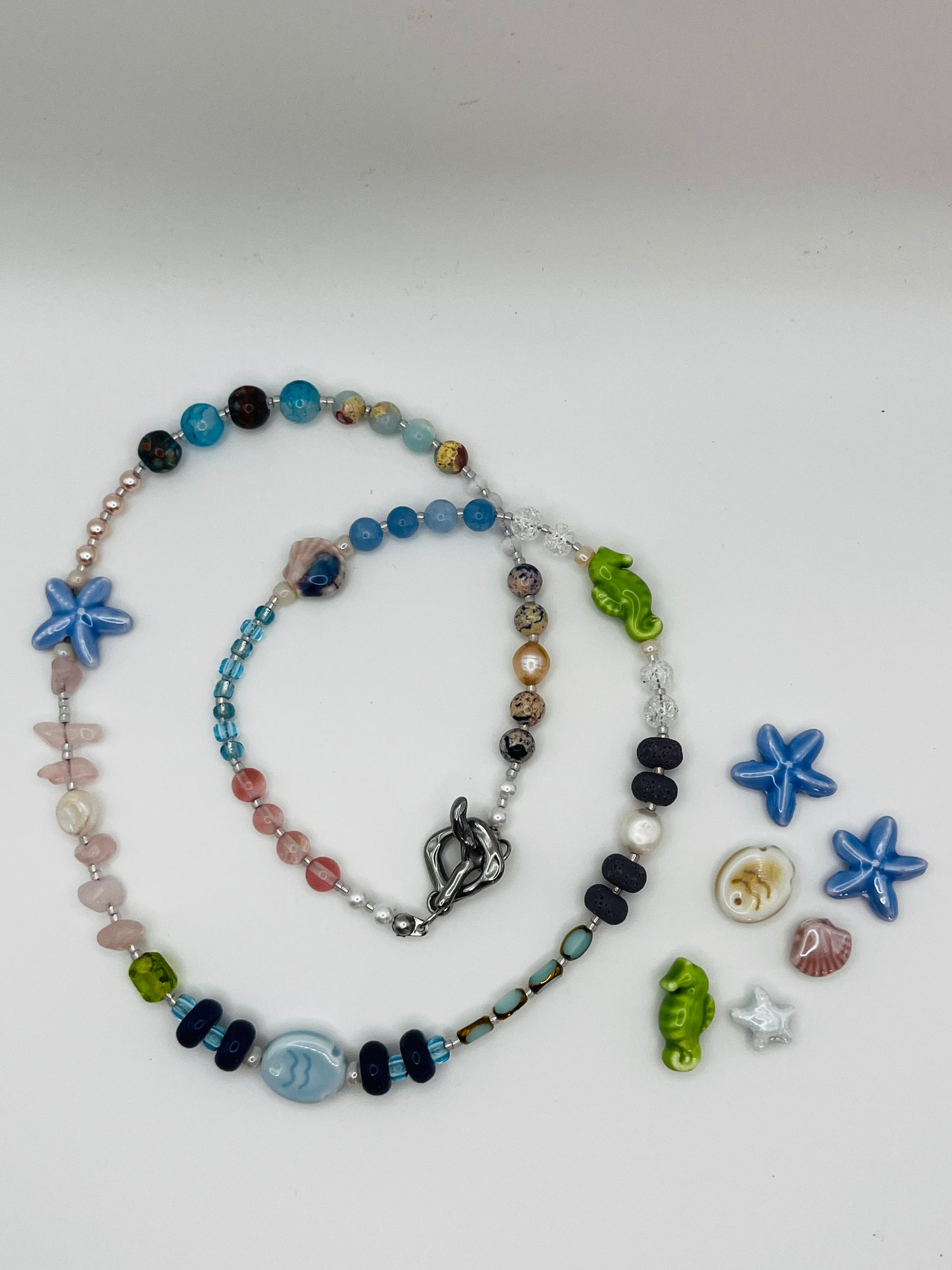 Collar Salina – collar largo enrollado con cuentas de aguamarina, cuarzo rosa, lava volcánica negra, perlas barrocas, estrella de mar y pez de cerámica azul, caballito de mar verde y cierre toggle plateado, con estrellas de mar, caballito, concha y estrella blanca sueltos, hecho a mano en Murcia