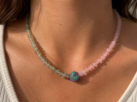 Collar Toulouse hecho a mano con cuentas rosas y verdes y pieza central multicolor, mostrado sobre el cuello de una modelo.