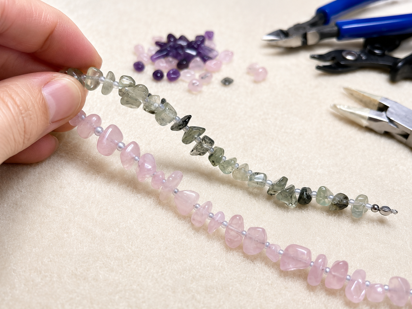 Collar Toulouse en proceso de elaboración artesanal con cuentas de piedra rosa y verde y herramientas de joyería.