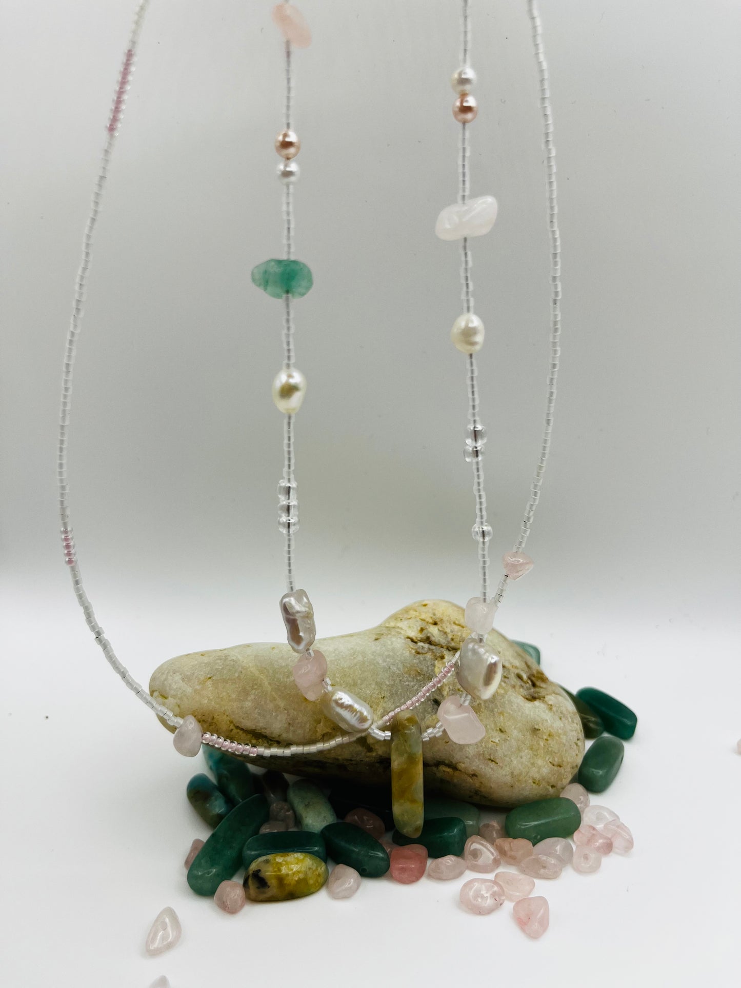 Collar Vera – doble collar colgado en vertical con semillas de rocalla blancas y transparentes, perlas barrocas cuadradas blancas, chips de cuarzo rosa, bolitas plateadas y cuenta alargada de jade verde oliva, sobre base de chips de jade verde y cuarzo rosa sueltos, hecho a mano en Murcia