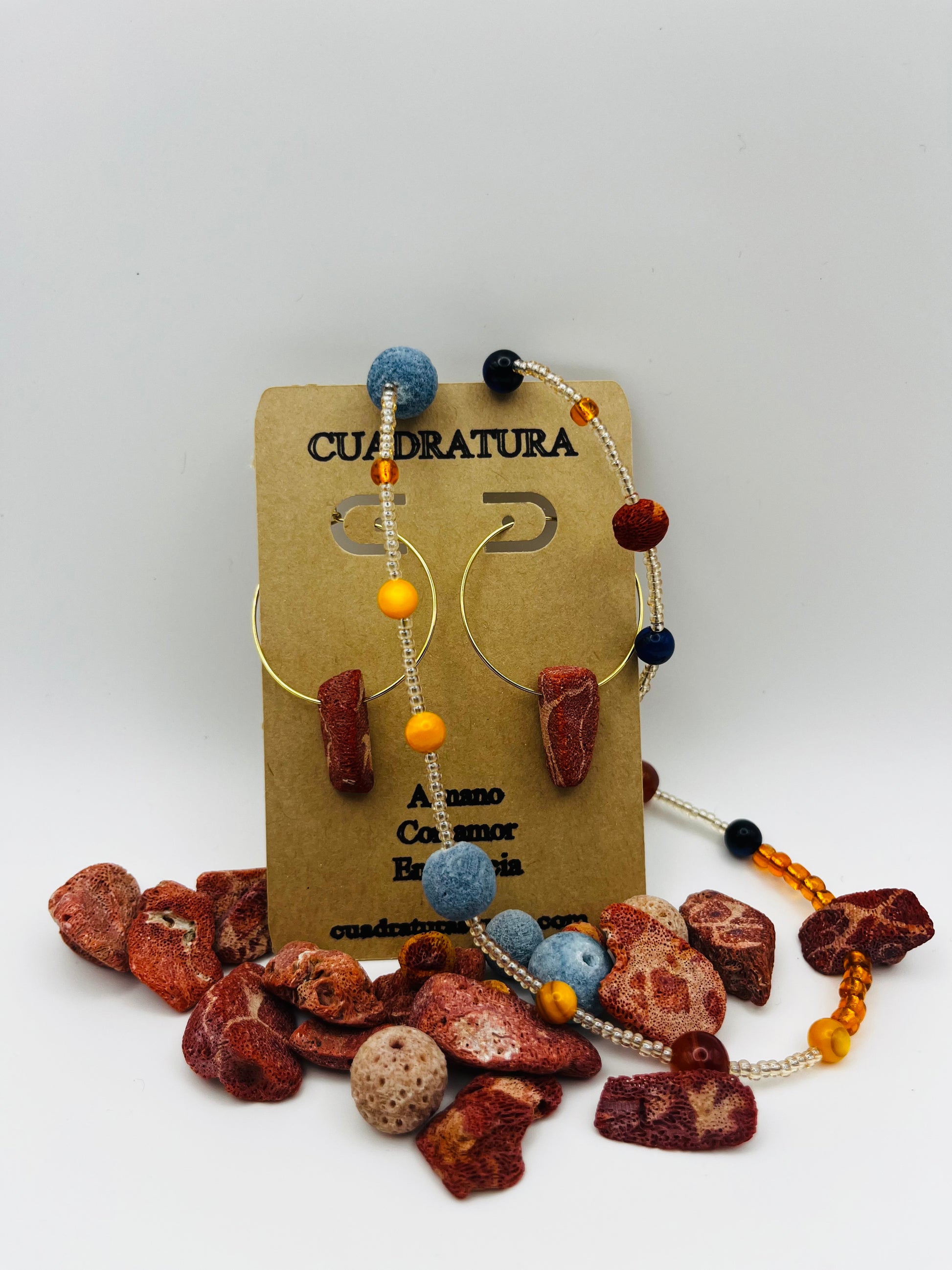 Conjunto Cala – pendientes de aro dorado con lava volcánica, ámbar amarillo y coral rojo natural, y pulsera Cala con lava volcánica, lapislázuli, ámbar y coral azul natural, hechos a mano en Murcia