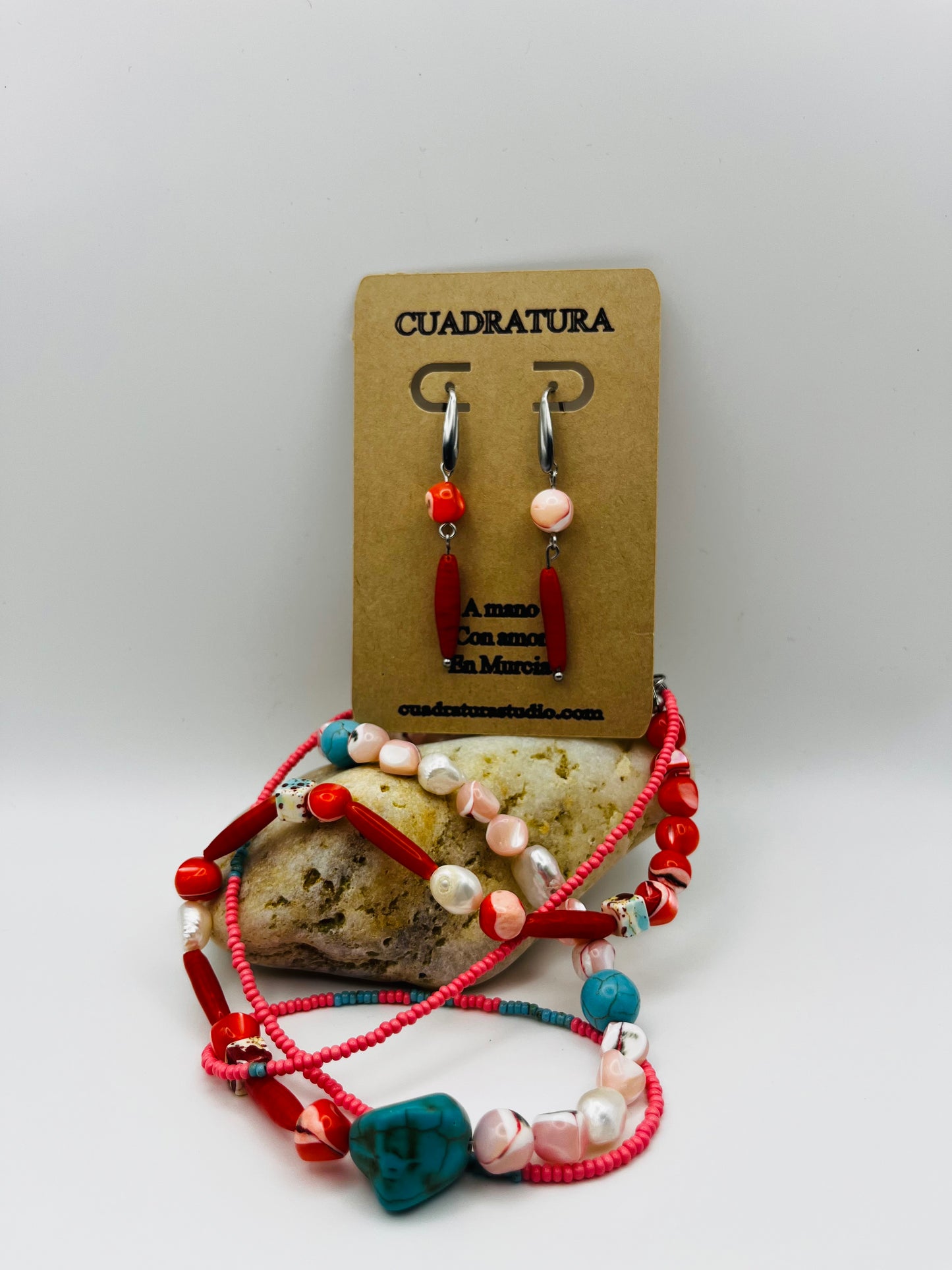 Conjunto Coral – collar doble con semillas de rocalla rosas, coral rojo, turquesa natural, nácar moteado y perlas barrocas, junto a Pendientes Coral con aro plateado, coral rojo y nácar rosa, en tarjeta Cuadratura, hechos a mano en Murcia