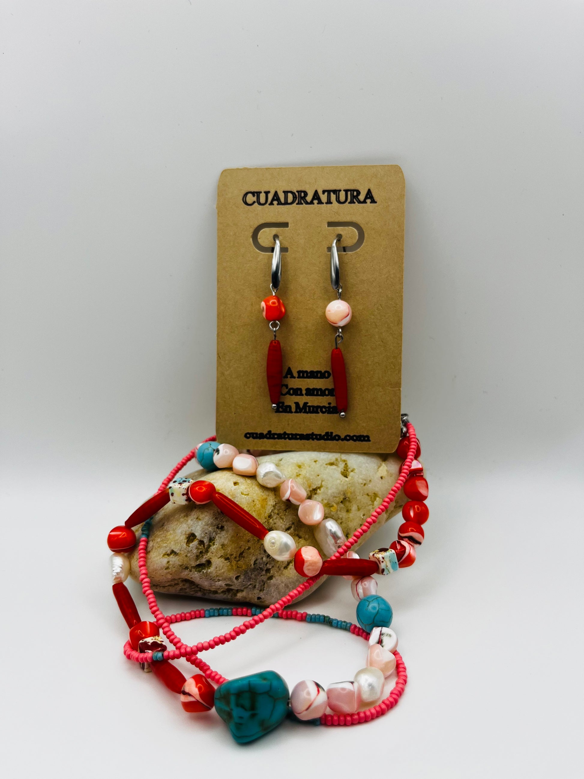 Conjunto Coral – collar doble con semillas de rocalla rosas, coral rojo, turquesa natural, nácar moteado y perlas barrocas, junto a Pendientes Coral con aro plateado, coral rojo y nácar rosa, en tarjeta Cuadratura, hechos a mano en Murcia