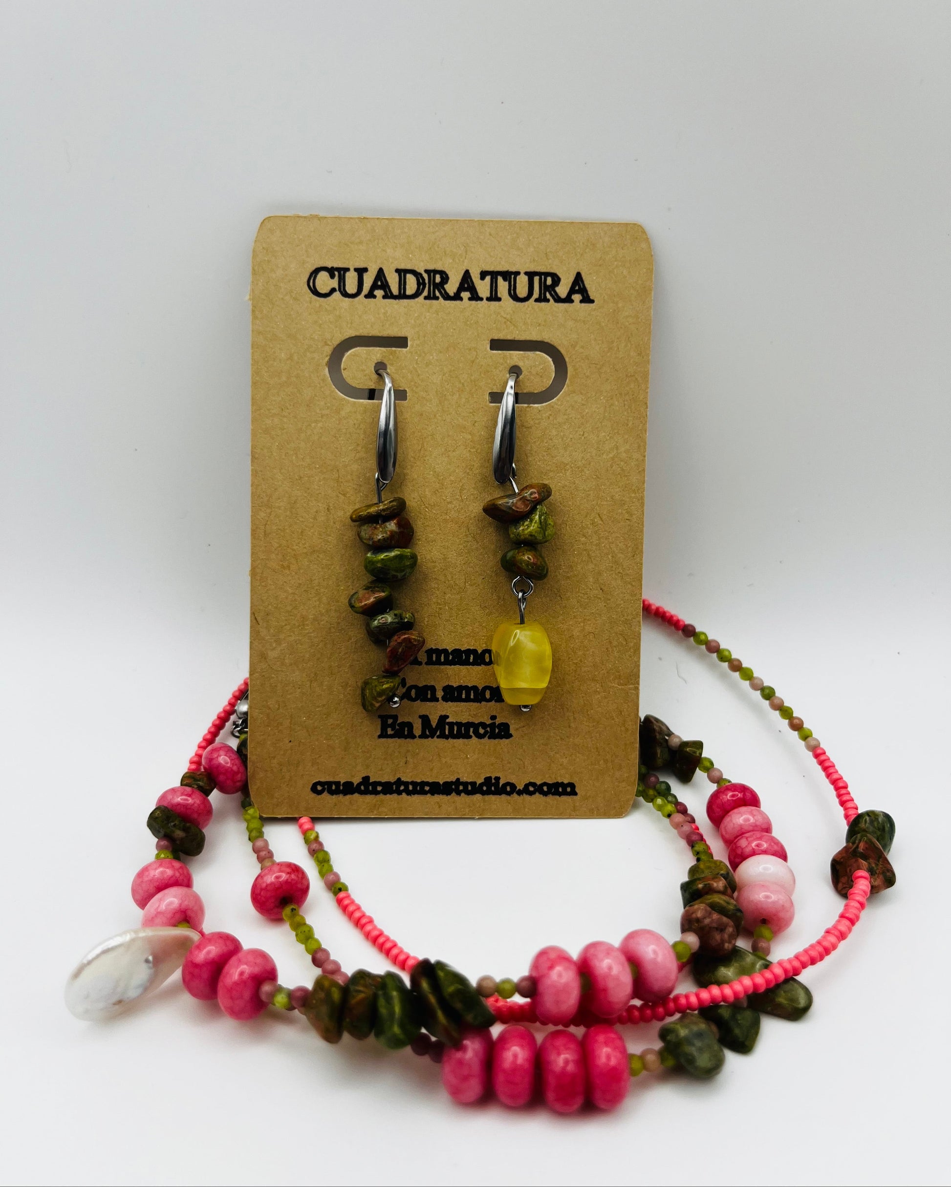 Conjunto Elena – collar doble con semillas de rocalla rosas, rodocrosita rosa, chips de turmalina verde y marrón, cuenta amarilla translúcida y concha de nácar, junto a Pendientes Elena asimétricos con chips de turmalina y cuenta amarilla translúcida en aro plateado, en tarjeta Cuadratura, hechos a mano en Murcia