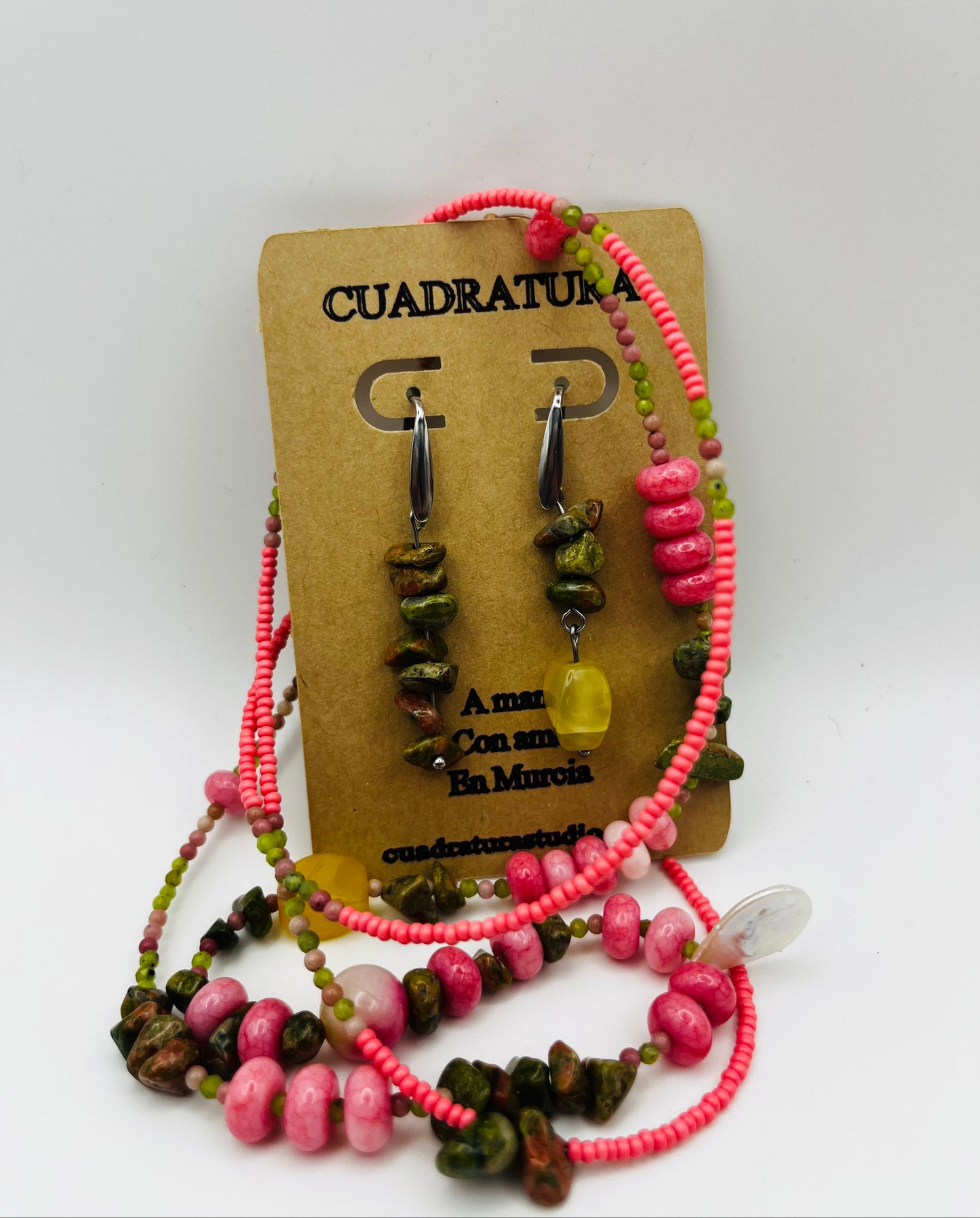 Conjunto Elena – collar doble con semillas de rocalla rosas, rodocrosita rosa, chips de turmalina verde y marrón, cuenta amarilla translúcida y concha de nácar, junto a Pendientes Elena con aro plateado, chips de turmalina verde y cuenta amarilla translúcida, en tarjeta Cuadratura, hechos a mano en Murcia