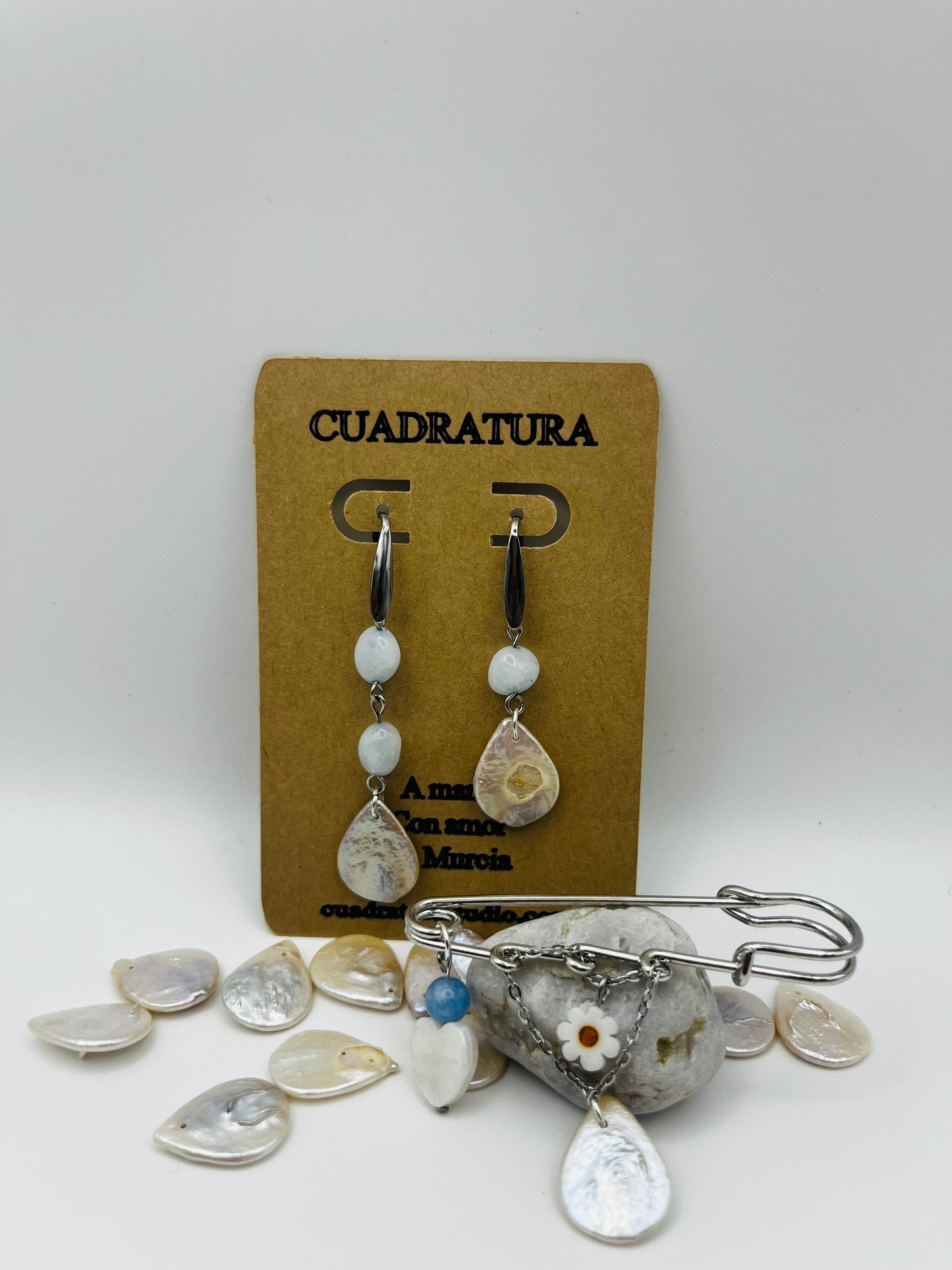 Conjunto Periwinkle – pendientes de aro plateado con cuenta ovalada blanca y pieza gota de nácar, y broche imperdible plateado con cuenta azul, flor de margarita y pieza gota de nácar, hechos a mano en Murcia