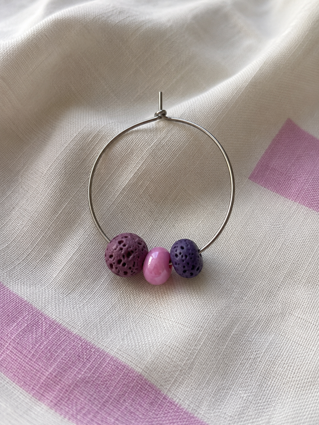 Pendiente Berry individual de aro en acero inoxidable con cuentas de piedra volcánica morada y cuenta de cristal rosa, hecho a mano.