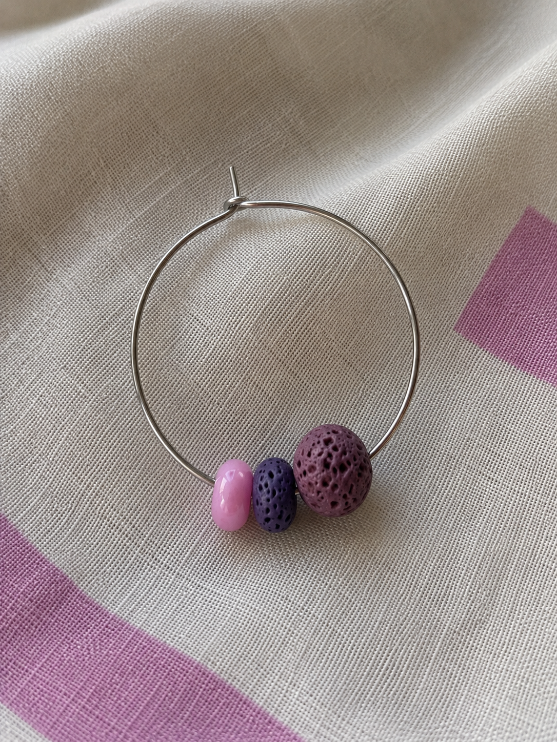 Pendiente Berry individual de aro en acero inoxidable con cuentas de piedra volcánica morada y cuenta de cristal rosa, en vista alternativa.
