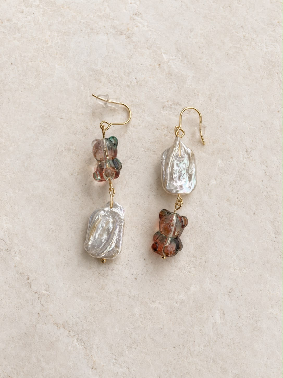 Pendientes Barroca Dulce hechos a mano con perlas barrocas y ositos de cristal en tonos suaves, sobre fondo de piedra beige.