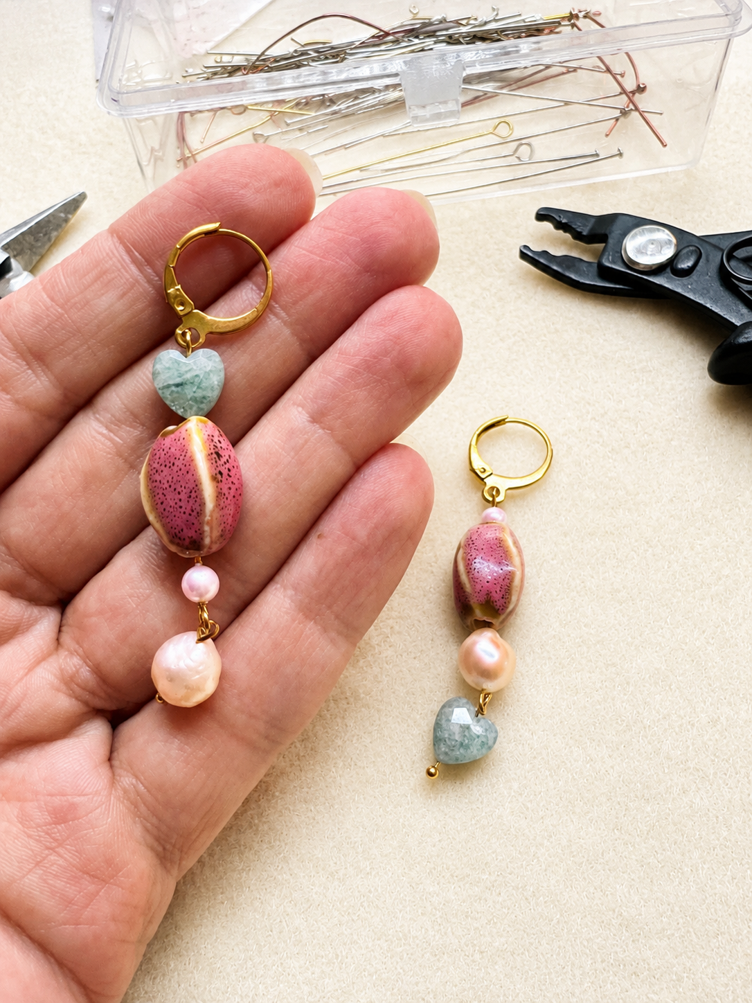 Pendientes Gaia durante el proceso artesanal, mostrando las dos variantes con corazones de amazonita, cerámica rosa y perlas de agua dulce.