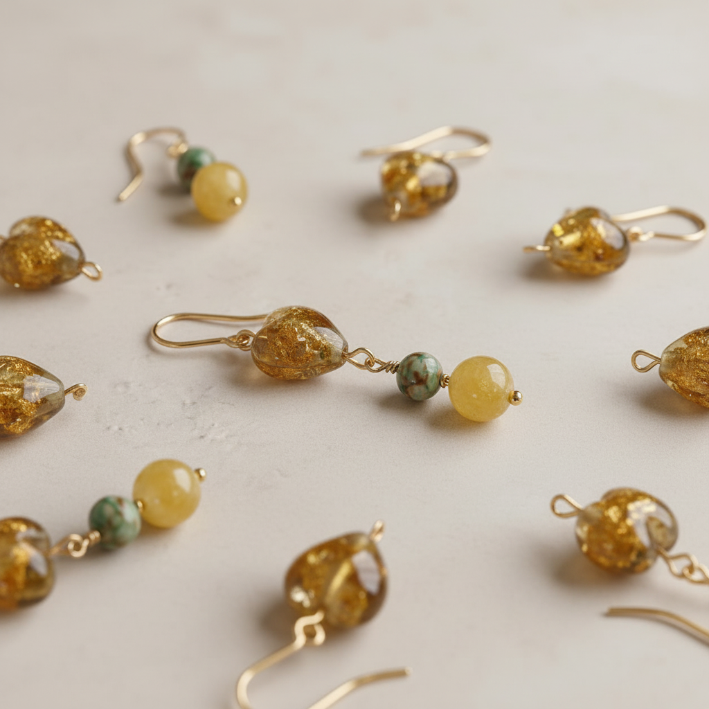 Composición de pendientes Miel hechos a mano con corazones de cristal dorado, piedras verdes y cuentas amarillas.
