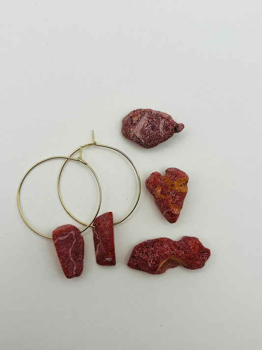 Pendientes Peñón – pendientes con aro dorado fino y dos piezas de coral rojo natural rugoso, con trozos de coral rojo natural sueltos esparcidos, sobre fondo blanco, hechos a mano en Murcia