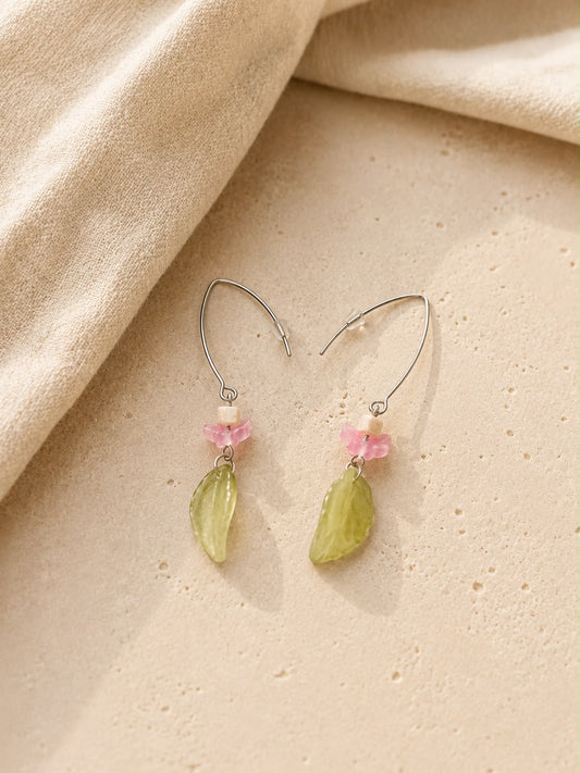 Pendientes Primavera hechos a mano con hojas verdes, pequeñas flores rosas y cierres plateados, sobre fondo de piedra beige.
