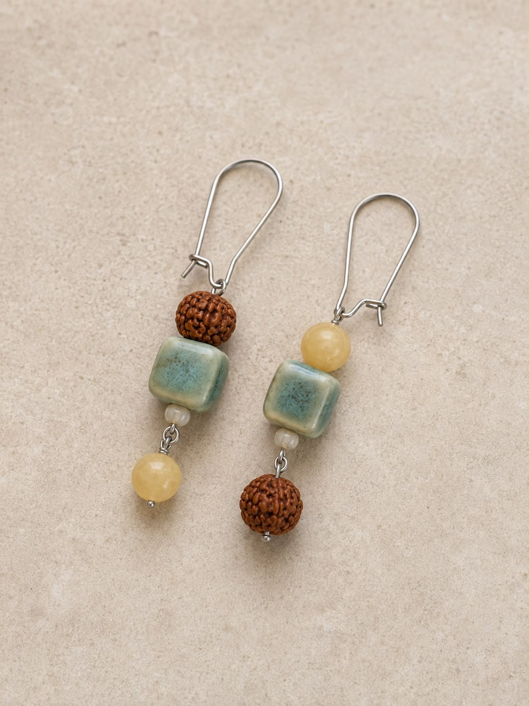 Pendientes Siena hechos a mano con cerámica artesanal verde, jade amarillo, cuentas de rudraksha y cierres plateados.