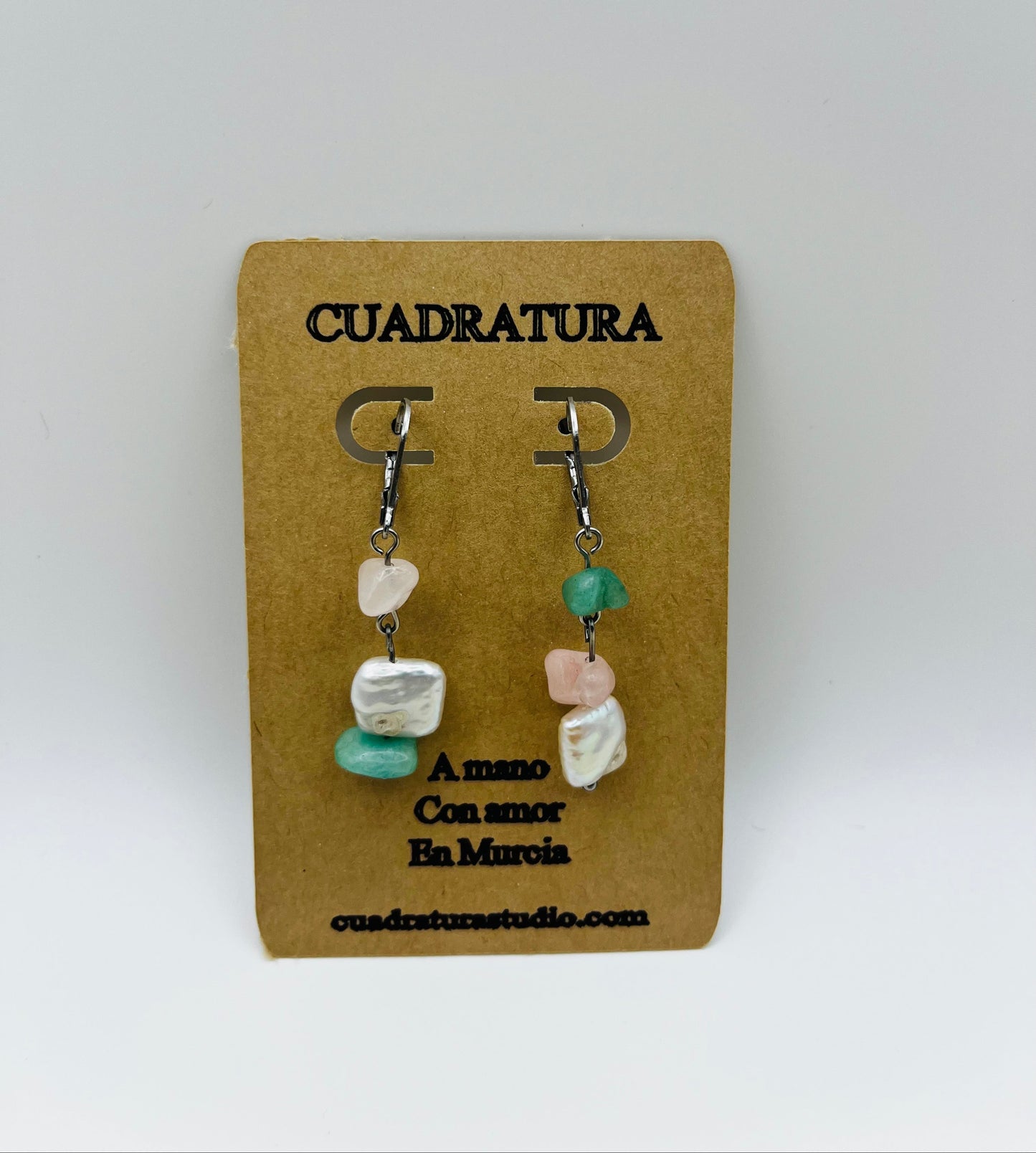 Pendientes Vera – pendientes simétricos con aro plateado, chip de cuarzo rosa, chip de amazonita verde menta y perla keshi blanca cuadrada, en tarjeta Cuadratura, fondo gris claro liso, hechos a mano en Murcia