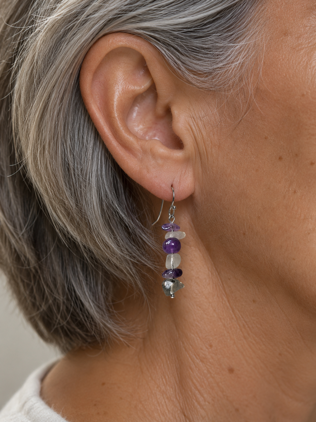 Pendientes Verena de amatista y fluorita natural sobre modelo de pelo canoso corto, con gancho de acero inoxidable.
