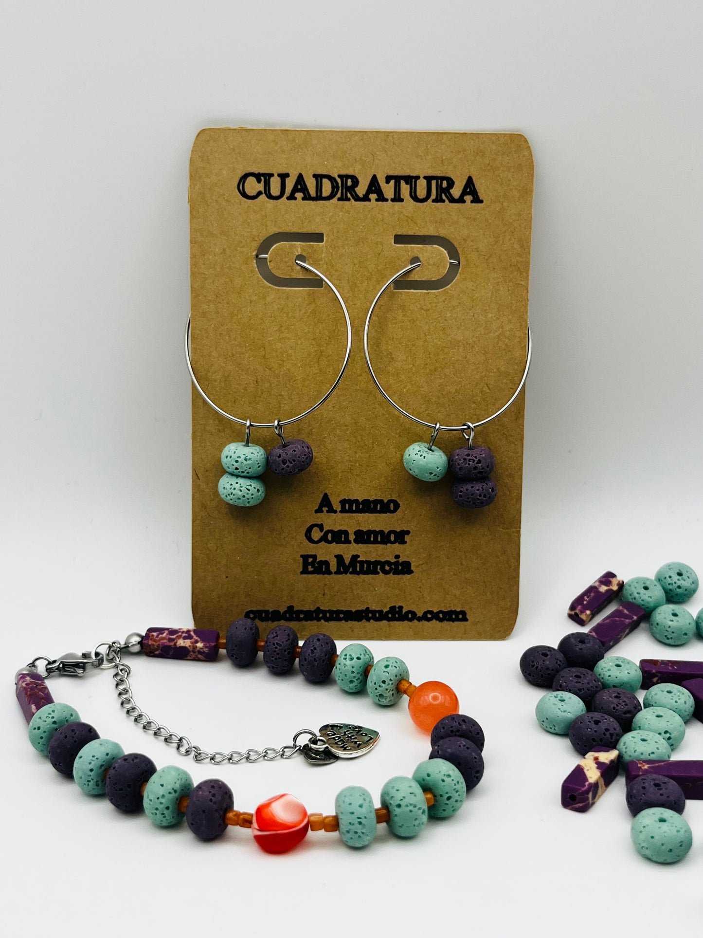 Conjunto artesanal Arrecife: pulsera y pendientes aro plateado con lava volcánica turquesa y morada, cornalina naranja y coral rojo, montados a mano en Murcia
