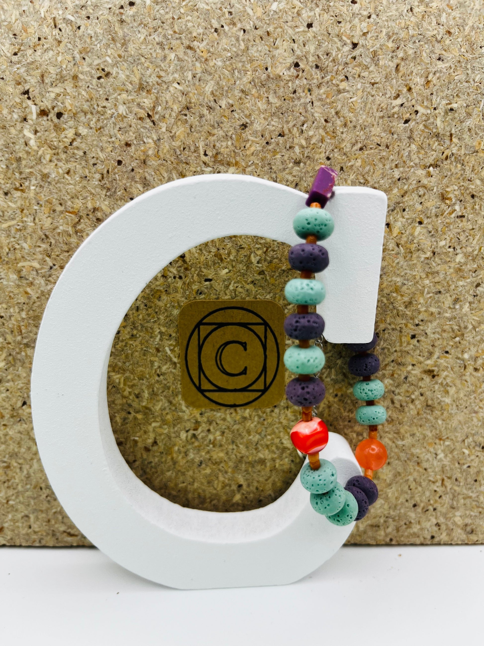 Pulsera artesanal Arrecife con lava volcánica turquesa y morada, cornalina naranja, coral rojo y howlita, montada a mano en Murcia
