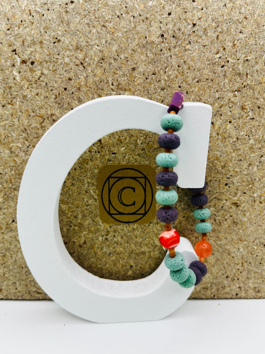 Pulsera artesanal Arrecife con lava volcánica turquesa y morada, cornalina naranja, coral rojo y howlita, montada a mano en Murcia
