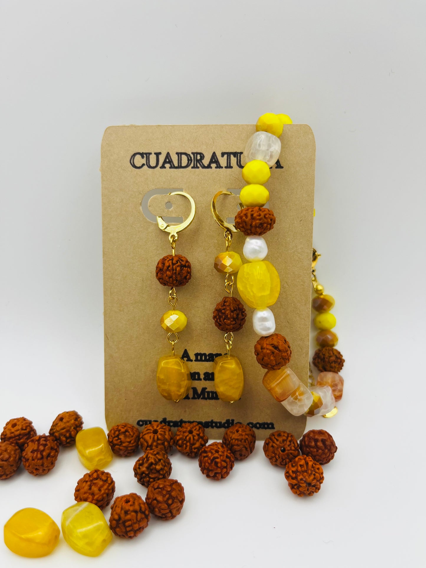 Conjunto artesanal Calima: pulsera y pendientes dorados con semillas de rudraksha, cristal amarillo y nácar, presentados en tarjeta Cuadratura, montados a mano en Murcia

