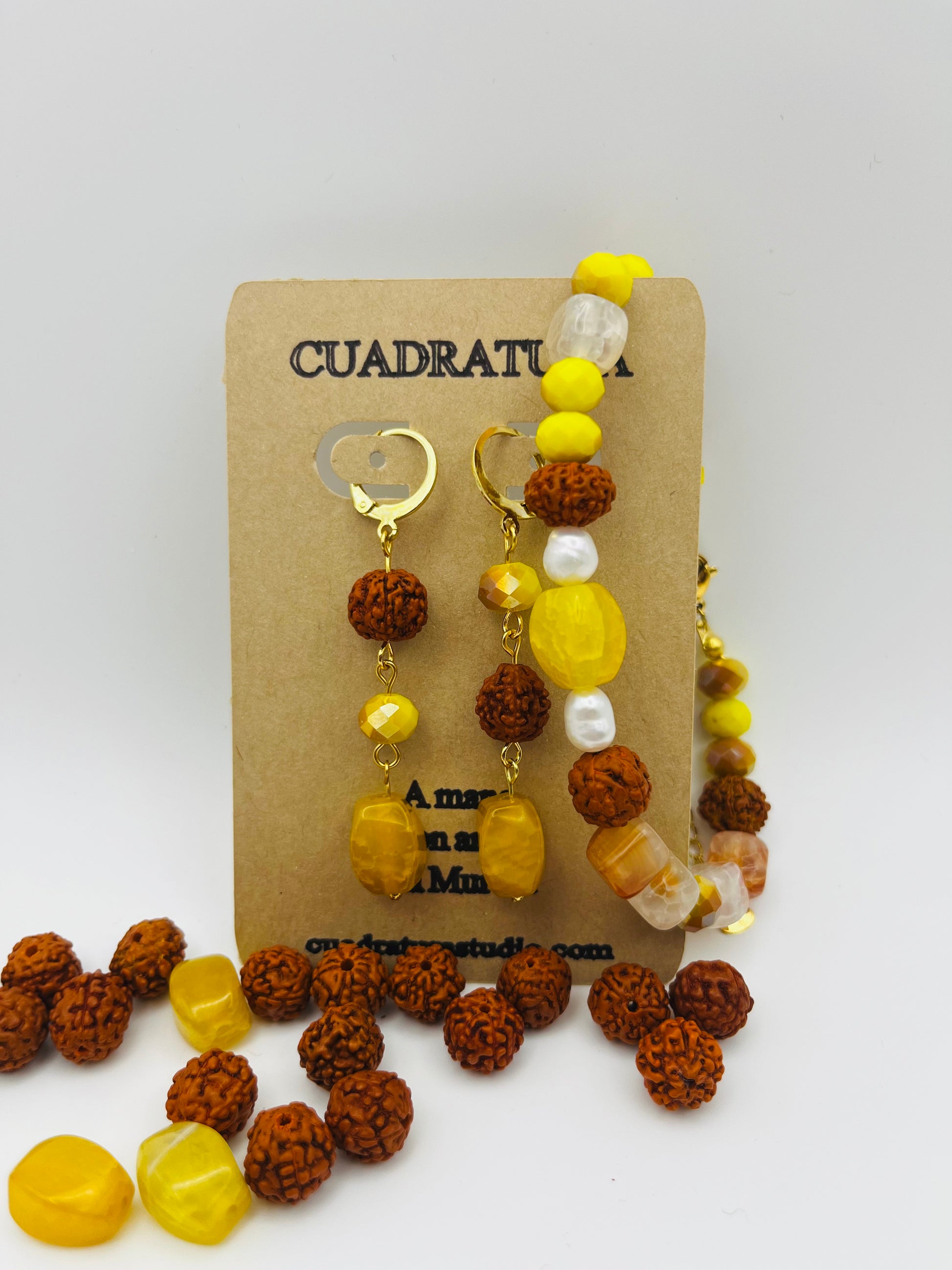 Conjunto artesanal Calima: pulsera y pendientes dorados con semillas de rudraksha, cristal amarillo y nácar, presentados en tarjeta Cuadratura, montados a mano en Murcia
