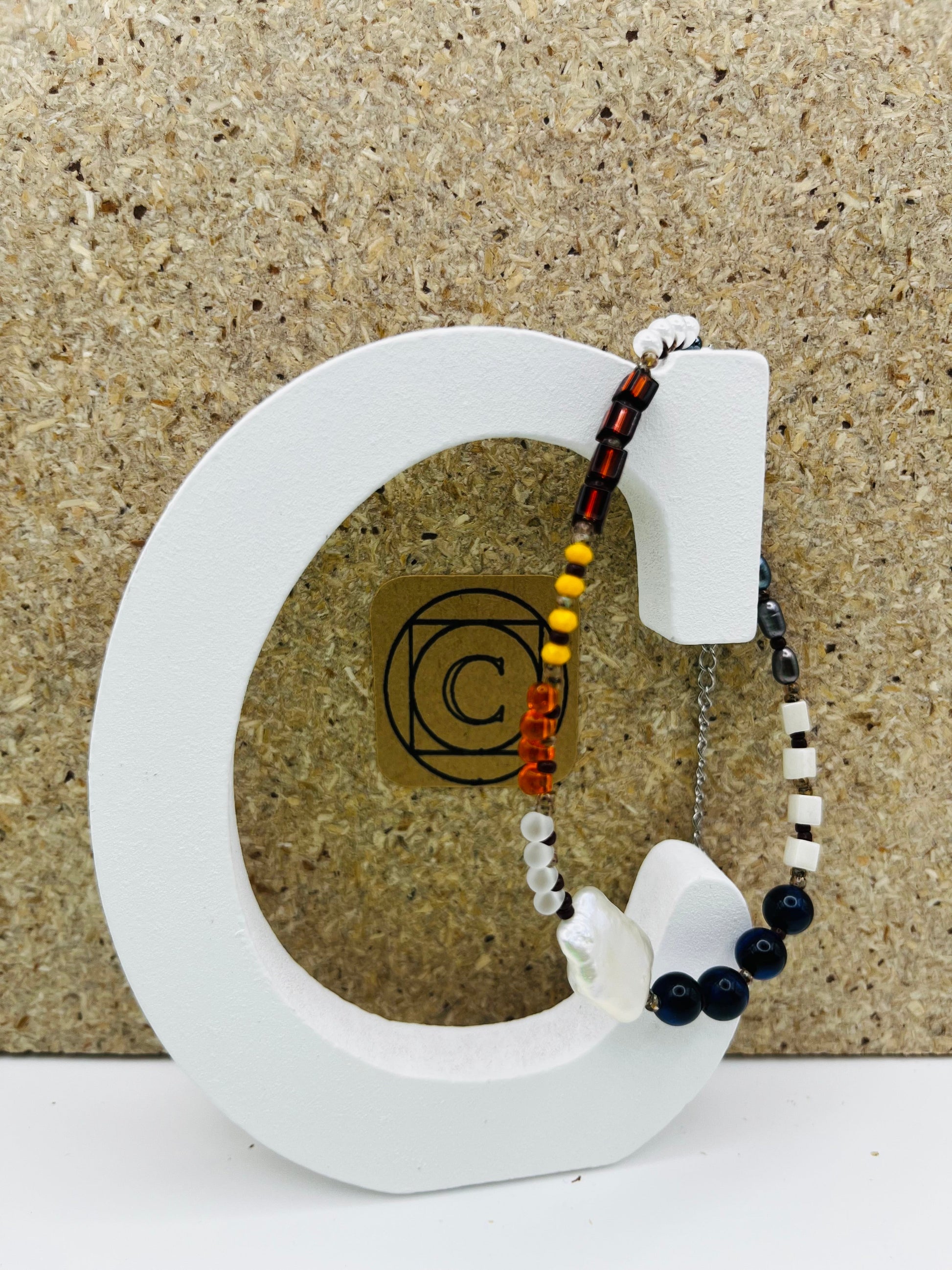 Pulsera artesanal asimétrica Solana con cristal granate, ámbar natural, perla barroca blanca, hematita y ónix azul marino, montada a mano en Murcia
